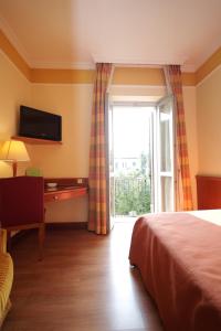 a bedroom with a bed and a desk and a window at Hotel Il Chiostro by LVG Hotel Collection in Verbania