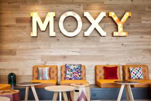 a restaurant with orange chairs and a mox sign on the wall at Moxy Rust in Rust