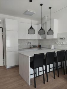 a white kitchen with black chairs and a counter at Apartman Waldy in Osijek