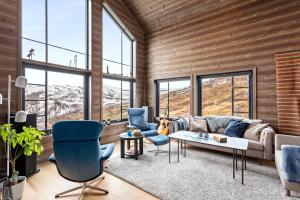 uma sala de estar com um sofá, cadeiras e janelas em Rindabakkane Lodge em Sogndal