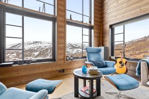 uma sala de estar com cadeiras azuis e uma guitarra em Rindabakkane Lodge em Sogndal