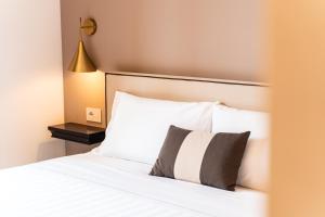 a bedroom with a bed with white sheets and a lamp at Hotel del Conte in Laveno-Mombello