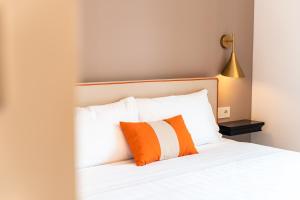 a bed with orange and white pillows and a lamp at Hotel del Conte in Laveno-Mombello