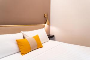 a bedroom with a bed with yellow and white pillows at Hotel del Conte in Laveno-Mombello