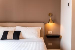 a bedroom with a bed with white pillows and a lamp at Hotel del Conte in Laveno-Mombello