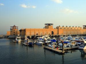 a group of boats docked in a harbor with a building at Hyatt Regency Al Kout Mall in Kuwait