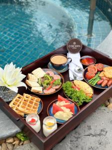 un vassoio pieno di diversi tipi di cibo accanto alla piscina di Cochin Sang Hotel ad Ho Chi Minh