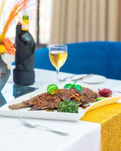 a plate of food on a table with a glass of wine at Hotel Sapphire in Mombasa