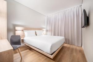 a bedroom with a white bed and a tv at Moov Hotel Lisboa Oriente in Lisbon