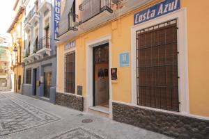 un edificio amarillo con una puerta en una calle en Hostal Costa Azul, en Granada