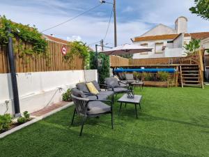 eine Terrasse mit Stühlen und einem Sonnenschirm auf dem Rasen in der Unterkunft Vila Maria Mix Dorm by HOST-POINT in Costa da Caparica