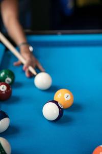 a woman playing pool with a cue and balls on a pool table at Aloft Strasbourg Etoile in Strasbourg