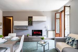 een woonkamer met een tafel en een televisie bij [SMART FLAT] Private Garage, Wi-Fi, Netflix in Castelletto sopra Ticino