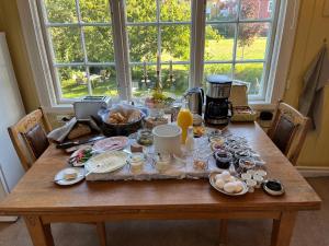 una mesa de madera con productos para el desayuno y una cafetera en Villa Wäring Husrum & Frukost, en Varberg