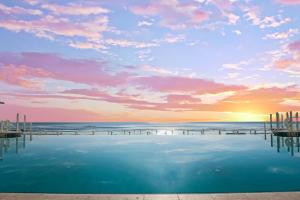 a pool on the beach with a sunset at Daytona Grande Oceanfront Resort in Daytona Beach