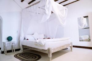 - une chambre blanche dotée d'un lit avec des rideaux blancs dans l'établissement Met Beach Resort Malindi, à Malindi