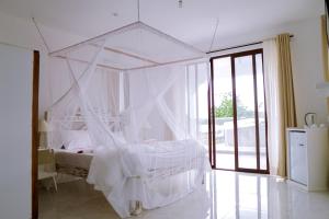 - une chambre avec un lit blanc à baldaquin dans l'établissement Met Beach Resort Malindi, à Malindi