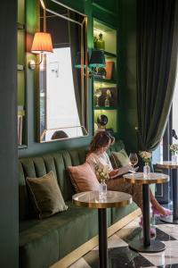 a woman sitting on a couch in a room with two tables at Hotel La Gemma in Florence