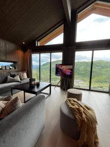 uma sala de estar com sofás e uma televisão e janelas em Sogndal Chalet em Sogndal