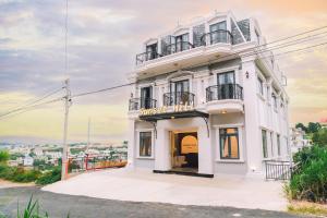 - un bâtiment blanc avec un balcon au-dessus dans l'établissement Sunset Hill Dalat, à Đà Lạt