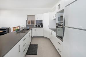 eine Küche mit weißen Schränken und einem Kühlschrank aus Edelstahl in der Unterkunft Large house 7 mins from Airport in Brisbane