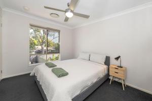 ein weißes Schlafzimmer mit einem Bett und einem Fenster in der Unterkunft Large house 7 mins from Airport in Brisbane