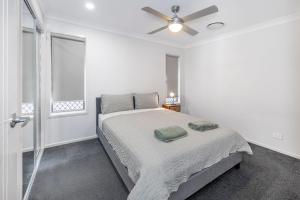 ein weißes Schlafzimmer mit einem Bett und einem Deckenventilator in der Unterkunft Large house 7 mins from Airport in Brisbane