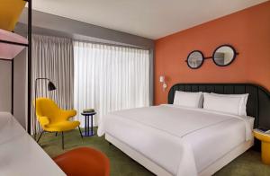 um quarto com uma cama grande e uma cadeira amarela em art'otel London Battersea Power Station, Powered by Radisson Hotels em Londres