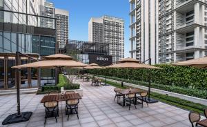 a patio with tables and chairs with umbrellas at Hilton Shenzhen World Exhibition & Convention Center - Only 5 minutes' walk to WECC in Shenzhen