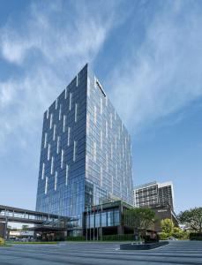 a tall glass building in front of a parking lot at Hilton Shenzhen World Exhibition & Convention Center - Only 5 minutes' walk to WECC in Shenzhen