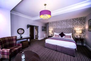 チェルトナムにあるDoubleTree by Hilton Cheltenham-Cotswoldsのベッドルーム1室(ベッド1台、ソファ、椅子付)