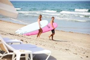 duas pessoas andando na praia com suas pranchas de surf em Beach Club at The Boca Raton em Boca Raton