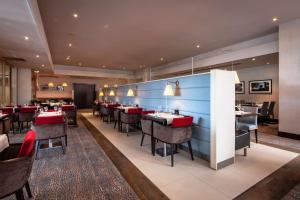 a dining room with tables and red chairs at Hilton Strasbourg in Strasbourg