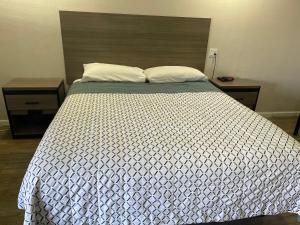 a bedroom with a bed with a white comforter and two tables at Town House Motel in Sanger