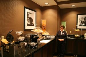 Eine Frau, die vor einer Theke mit Essen steht. in der Unterkunft Hampton Inn & Suites Detroit/Airport Romulus in Romulus