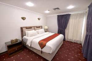 a bedroom with a large bed with purple curtains at Carlton Tower Hotel Kuwait in Kuwait