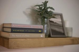 a stack of books sitting on a shelf with a mirror at Stylish & Renovated Modern Farmhouse Boutique Apt in Gainesville