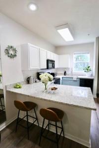 a kitchen with a counter with two stools and a counter top at Stylish & Renovated Modern Farmhouse Boutique Apt in Gainesville