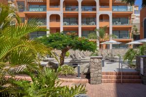 a building with a palm tree in front of it at Arguineguín Park By Servatur in La Playa de Arguineguín