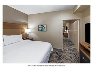 een hotelkamer met een wit bed en een hal bij Candlewood Suites DFW Airport North - Irving, an IHG Hotel in Irving