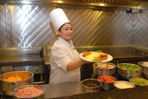 een vrouw in een keuken met een bord eten bij Embassy Suites by Hilton Dallas-Love Field in Dallas