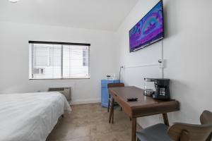 a bedroom with a bed and a desk and a tv at Starlite Hotel in Miami Beach