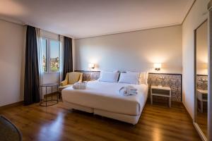 una habitación de hotel con una gran cama blanca y una silla en Hesperia Córdoba, en Córdoba