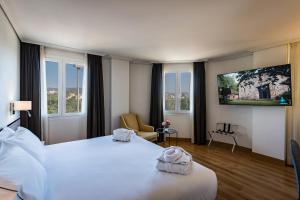 una habitación de hotel con una gran cama blanca y ventanas en Hesperia Córdoba, en Córdoba