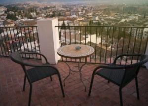 d'une table et de deux chaises sur un balcon avec vue. dans l'établissement Carmen de la Alcubilla del Caracol, à Grenade