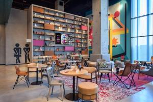 a restaurant with tables and chairs and a book shelf at Moxy Lisboa Oriente in Lisbon