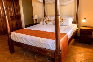 1 dormitorio con cama con dosel y sábanas blancas en Sand and Shells Beach House- 4 Bedroom with a pool, en Mombasa