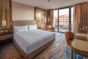 um quarto com uma cama e uma sala de estar com uma secretária em Doubletree By Hilton Antalya City Centre em Antália