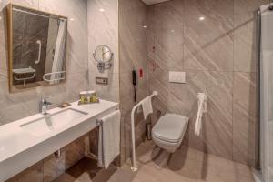 uma casa de banho com um lavatório, um WC e um espelho. em Doubletree By Hilton Antalya City Centre em Antália