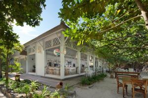 a building with tables and chairs and trees at Sempiak Seaside Resort in Selong Belanak